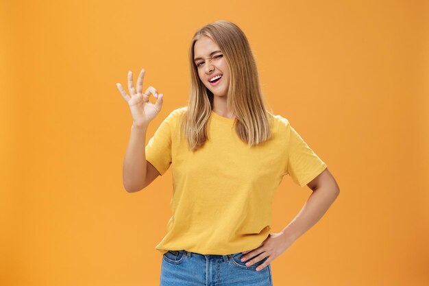 Happy young woman standing against yellow background