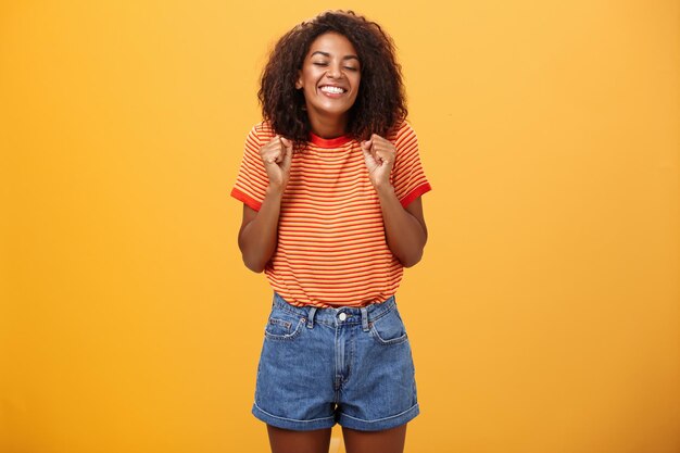 Happy young woman standing against yellow background