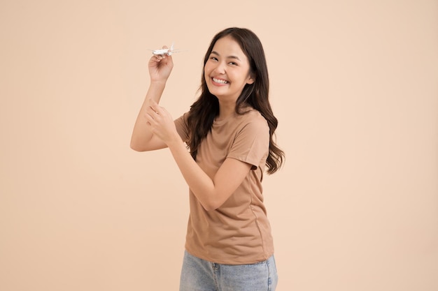 Happy young woman standing and holding a white toy plane dreamer in the studio