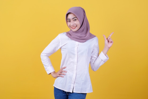 Happy young woman standing with her finger pointing right side wearing hijab