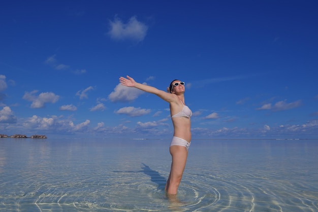 счастливая молодая женщина на летних каникулах на красивом тропическом пляже весело проводит время, наслаждается и расслабляется