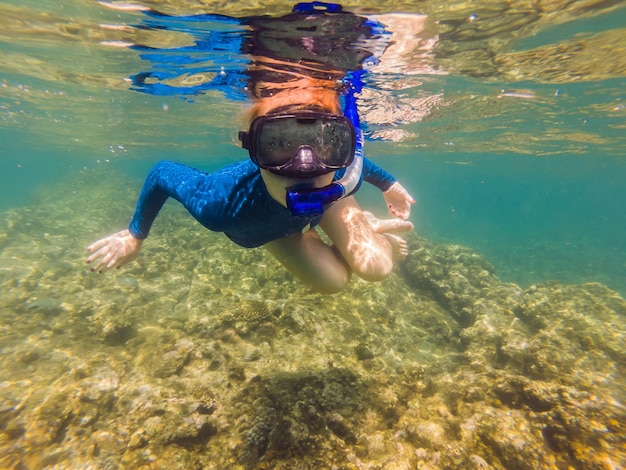 熱帯の海で水中を泳ぐ幸せな若い女性