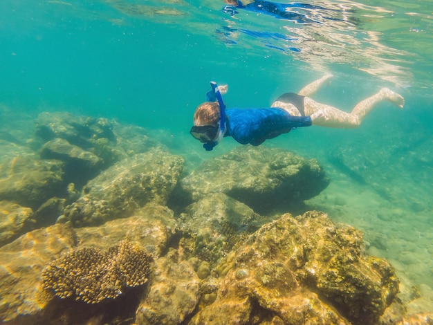 Happy young woman swimming underwater in the tropical ocean