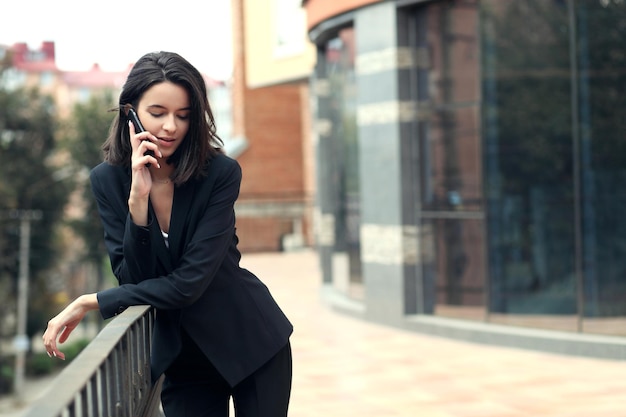 Happy young woman talking on mobile phone at city street lifestyle portrait