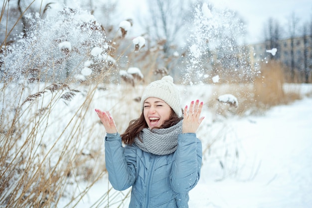 晴れた冬の日に空気中に雪を投げて幸せな若い女