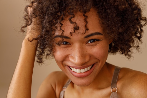 Giovane donna felice che tocca i capelli puliti nell'interiore dello studio