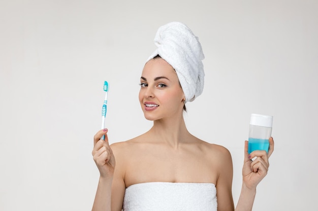 Happy young woman in towel brush her teeth