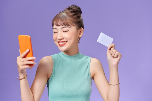 Счастливая молодая женщина с помощью мобильного телефона и кредитной карты
