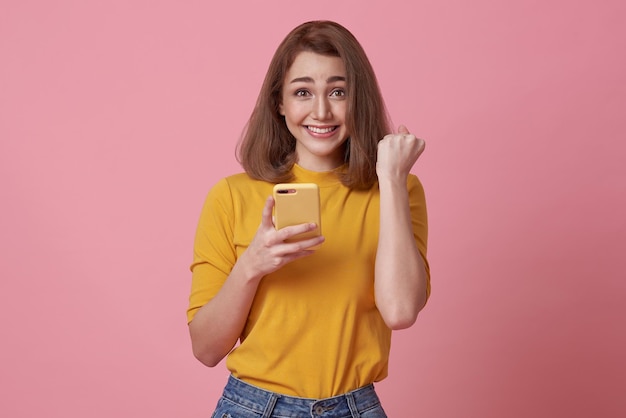 Happy young woman using mobile phone and hand gesture success celebrate