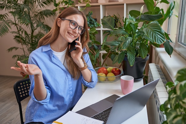 Happy young woman using mobile phone at home