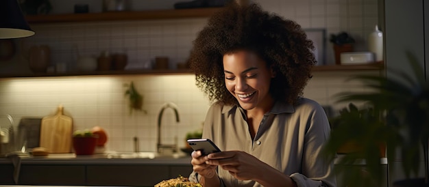 Happy young woman using phone while preparing meal at home casual female leaning on table browsing texts and smiling