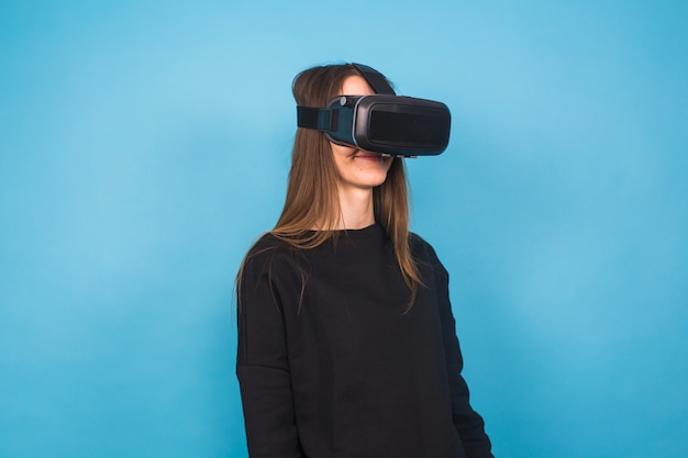 Happy young woman using a virtual reality headset on blue