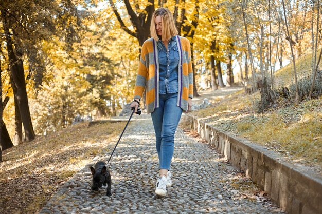 happy young woman walk with French Buldog outdoors in autumn