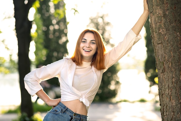 Happy young woman wearing casual clothes enjoying warm day in summer park .