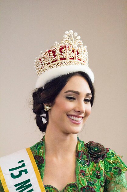 Foto felice giovane donna che indossa la corona contro il muro al concorso di bellezza