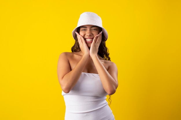 Happy young woman wearing a white dress on a yellow background