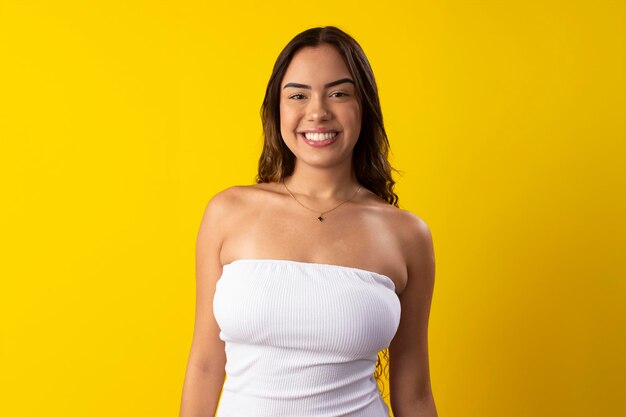 Happy young woman wearing a white dress on a yellow background