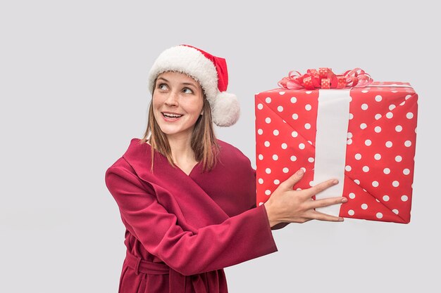 Happy young woman wears a red coat and Christmas hat