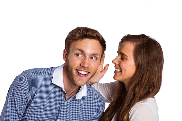 Happy young woman whispering secret into friends ear