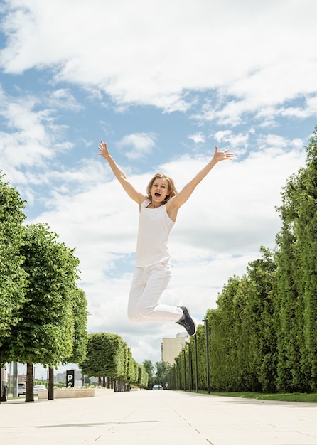 Happy young woman in white t-shirt jumping and screaming in the street