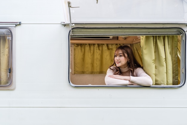 Happy young woman at window of a camper RV van motorhome