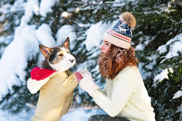 彼女の犬と雪の中で遊ぶ冬の幸せな若い女性