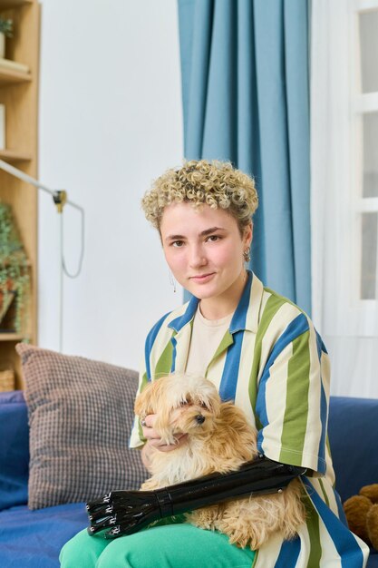 Happy Young Woman With Arm Prosthesis Playing With Cute Dog On Couch