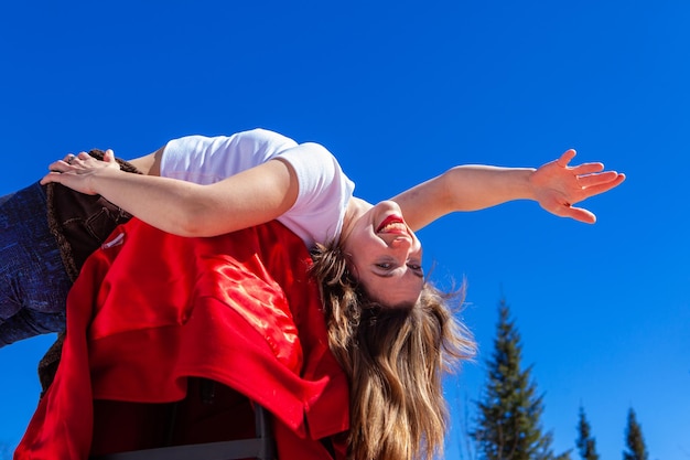 Happy young woman with arms outstretched against blue sky