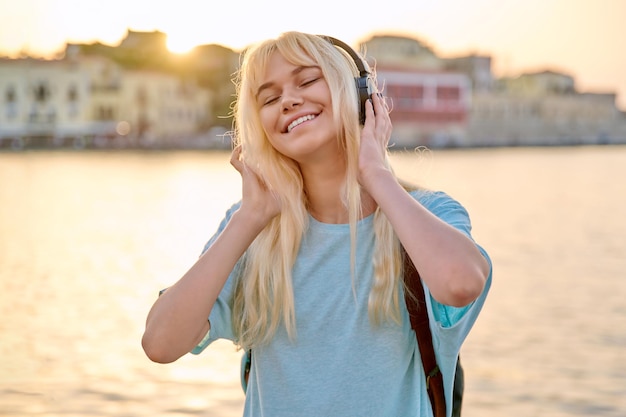 Happy young woman with backpack in headphones listening to music