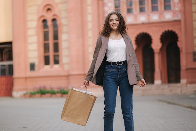 Happy young woman with bags after shopping Attractive female with curly hair spin around and smile