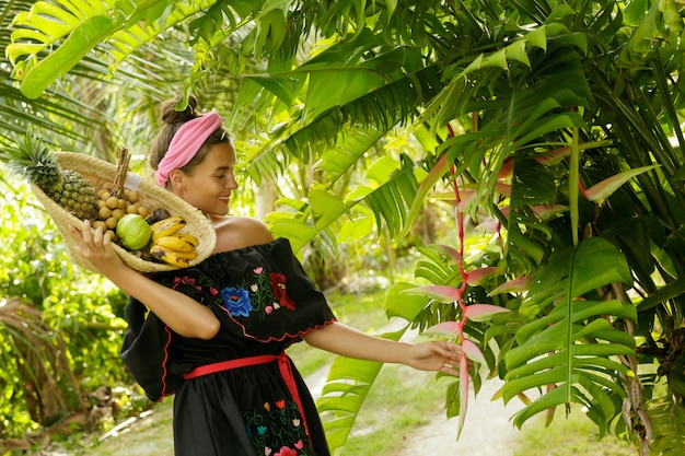 Foto felice giovane donna con un cesto pieno di frutti esotici