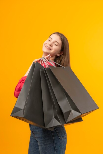 Happy young woman with big shopping bad on bright yellow background Woman smiles after good shopping Vertical frame