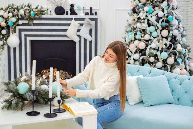 Photo happy young woman with book at christmas at home on background of christmas decorations