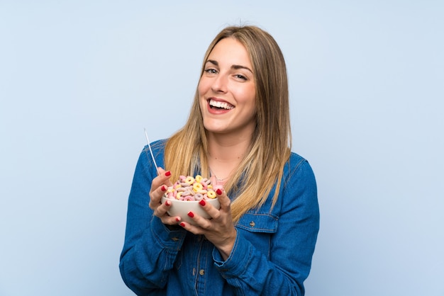 Photo happy young woman with bowl of cereals over isolated blue wall