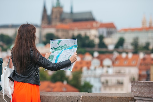 유럽에서 휴가를 보내는 동안 야외에서 지도를 들고 도시 지도를 들고 있는 행복한 젊은 여성
