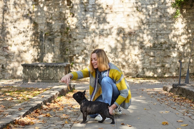 Happy young woman with french bulldog outdoors