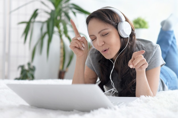 Happy young woman  with headphones and laptop at home