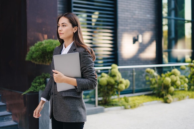 写真 朝仕事に行く街の通りを歩いてラップトップを持つ幸せな若い女水平コピー スペース教育概念海外で働く