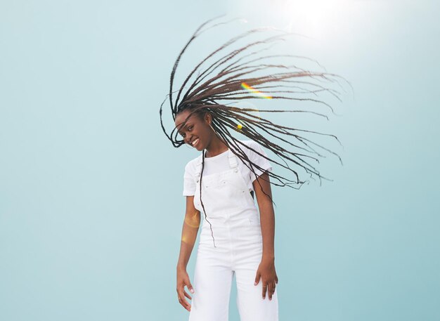 Photo happy young woman with long braids having fun against blue wall