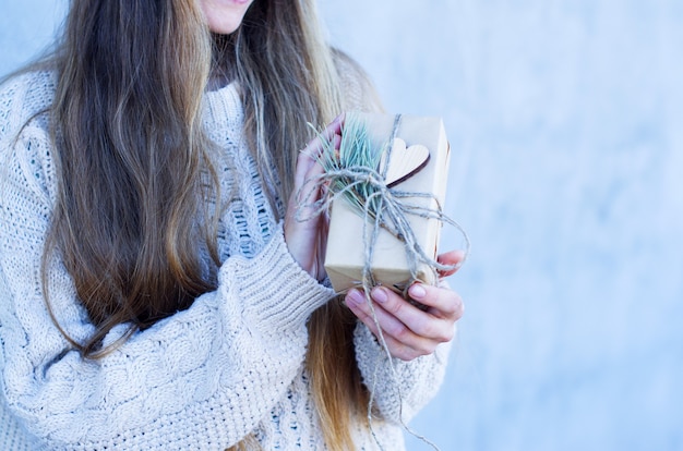 Счастливая молодая женщина с длинными волосами, держащая рождественскую подарочную коробку, рождественские подарки и новый год