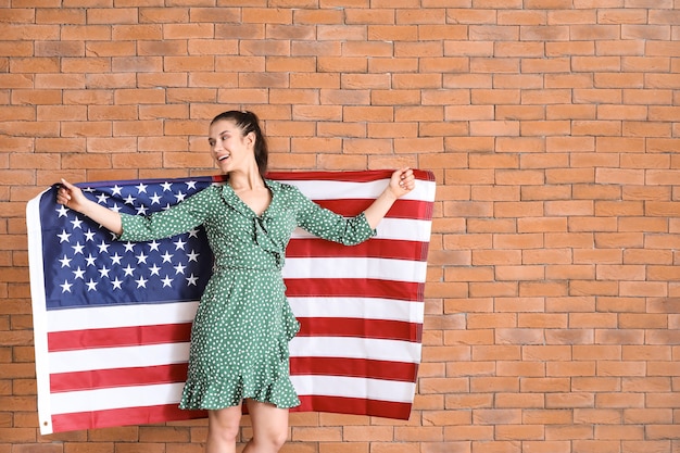 Photo happy young woman with national flag of usa on brick background