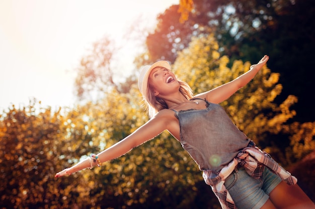 Photo happy young woman with open arms having fun in the nature in autumn.