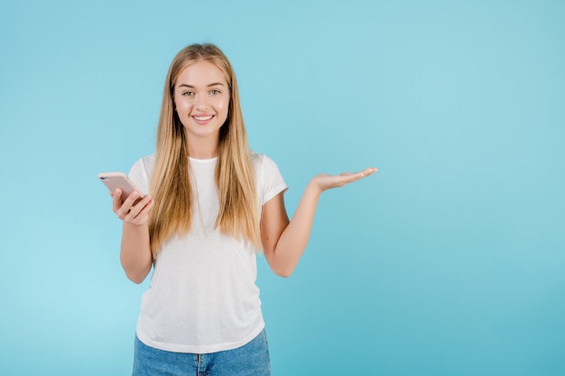 Happy young woman with phone in hand isolated over blue