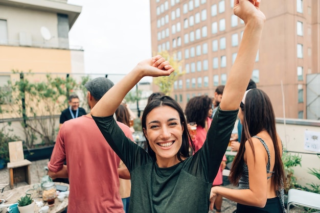 大学生のパーティーで踊りながら腕を上げて幸せな若い女性