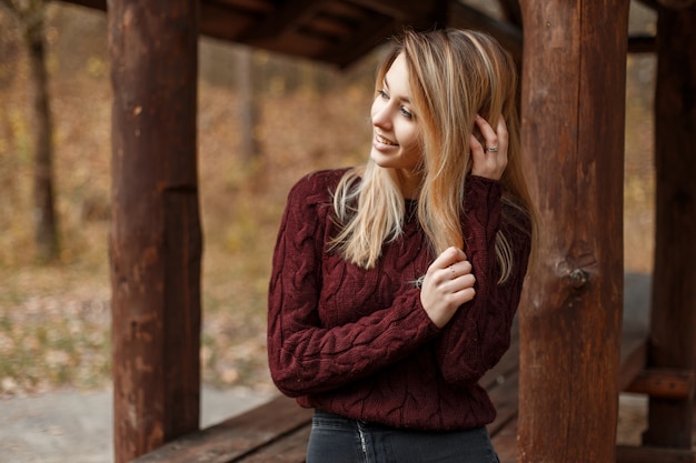 Happy young woman with a smile in a vintage knitted sweater outdoors