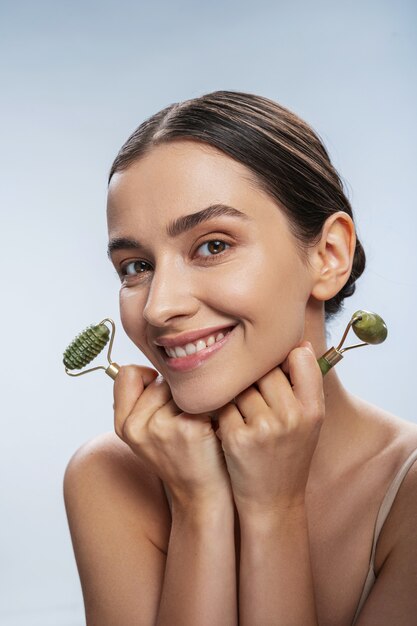 Happy young woman with two jade rollers