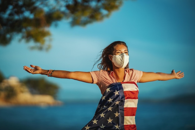 Happy young woman with US national flag and protective N95 mask during preventing the spread of the epidemic and treating coronavirus and pandemic COVID-19.