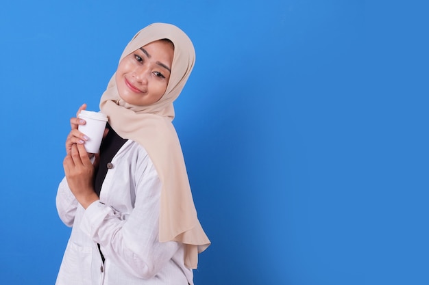 Happy of young woman with white shirt and wearing veil holding cup of coffee