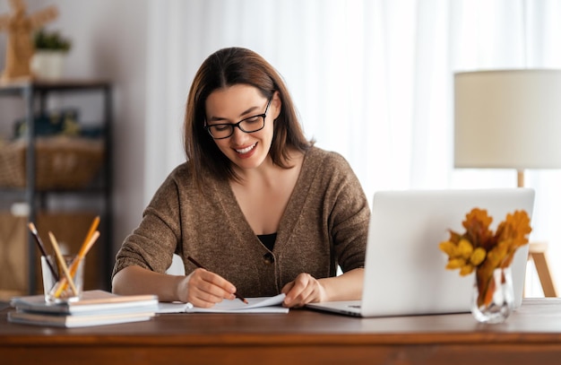 Счастливая молодая женщина, работающая в Интернете, смотрит веб-семинар, подкаст на ноутбуке, имеет удаленный разговор дома.