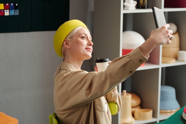 Happy young woman in yellow beret and casualwear taking selfie